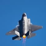 Extremely  close tail view of an F-35 Lightning II  in a high G turn, with afterburner on and  condensation trails at the wings root